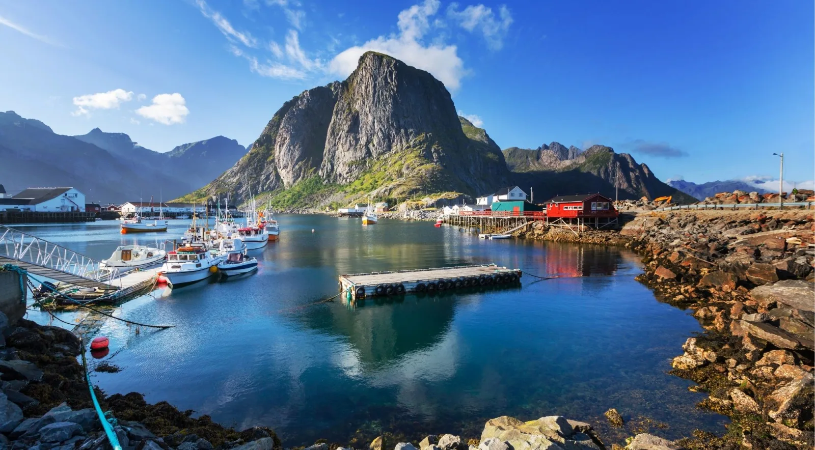 Elevated view over Reine's turquoise water and dramatic granite peaks on a clear summer day