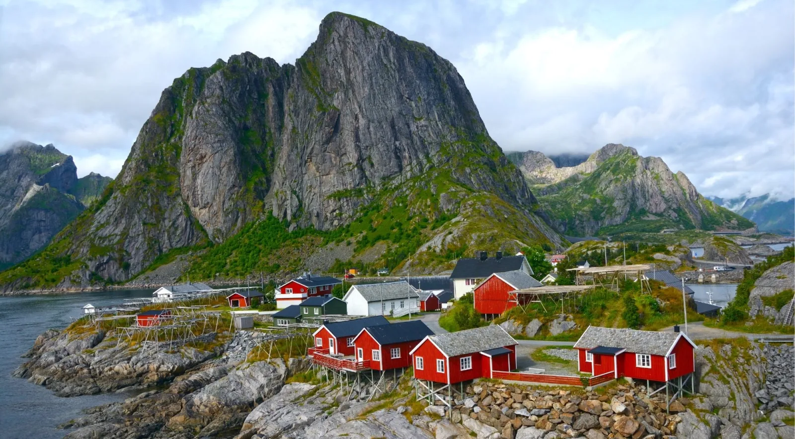 Traditional red cabins nestled below the jagged peaks above Reine, Lofoten