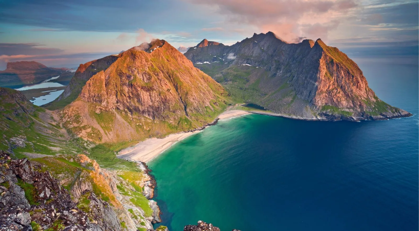 The turquoise crescent of Kvalvika Beach framed by mountains, seen from above