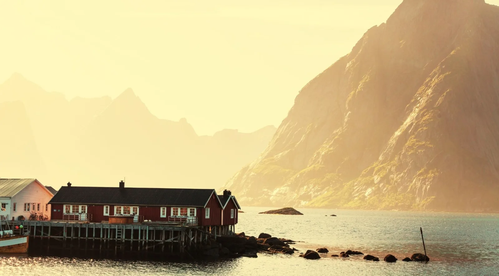 Golden light over Lofoten's mountains with a solitary shoreline rorbu