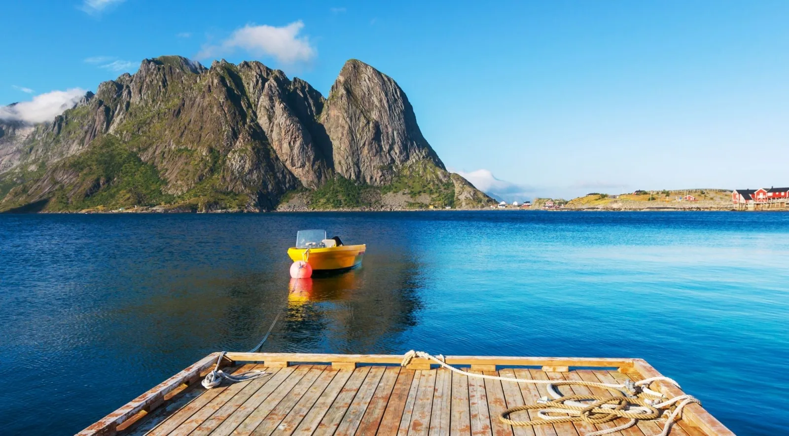 A red rowboat on glassy turquoise water below Lofoten's peaks